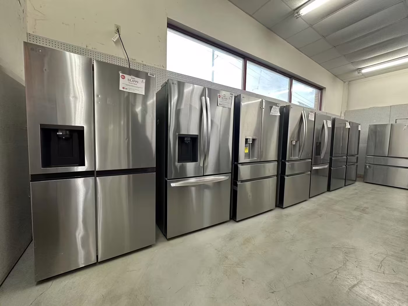 French-door and side-by-side refrigerators with price tags on the showroom floor